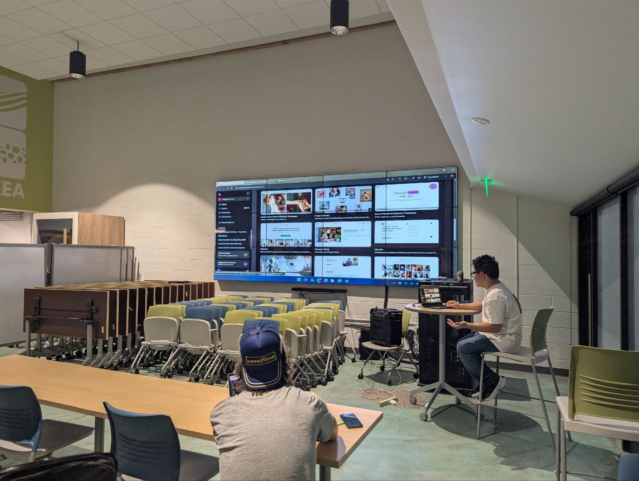 Instructor demonstrating a live AI build on the screen wall
